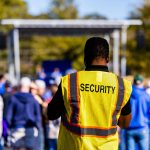 A security guard monitors a crowd at an outdoor event, ensuring safety and order.